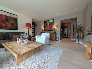 A modern living room with a wooden coffee table, white sofa, and a large abstract painting on the wall.