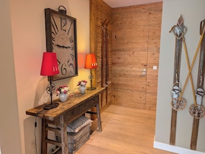 A wooden desk with a clock, two lamps, and a vase with flowers.
