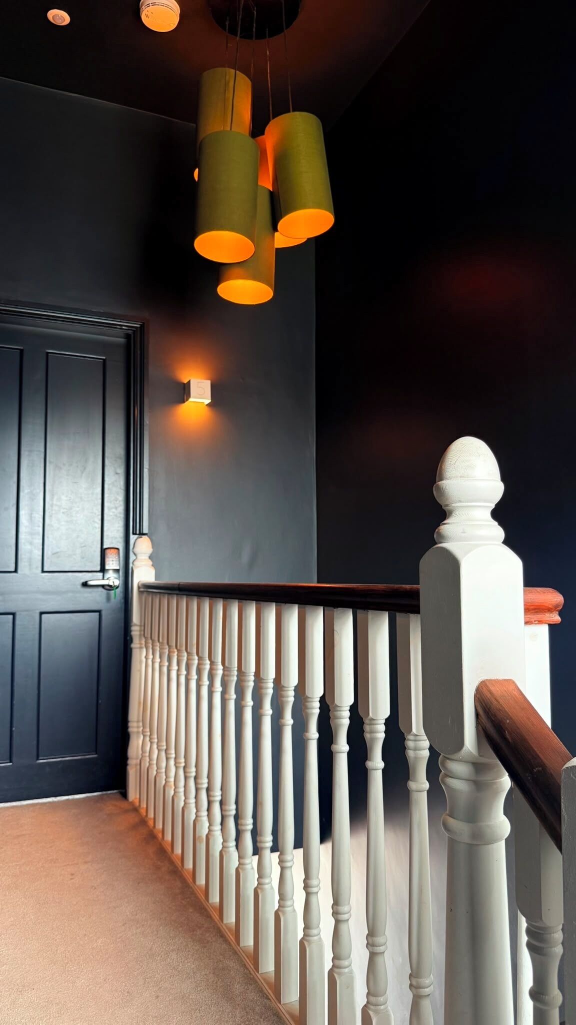 A staircase with white balusters, a dark wall, and a door with a light switch.