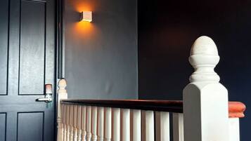 A staircase with white balusters, a dark wall, and a door with a light switch.