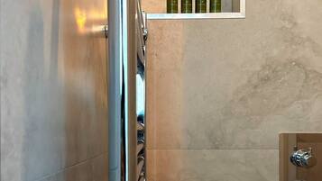 Un baño con zona de ducha, estante con botellas y un perchero para toallas.