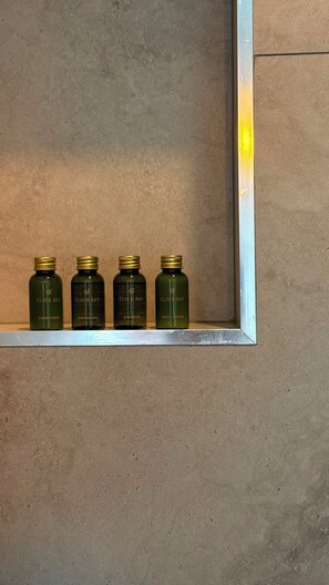 Four bottles of Elm & Bay products in a metal-framed shelf against a textured wall.