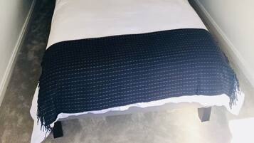A hotel room with a bed, pillows, a blanket, and a hanging light fixture.