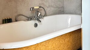 Un baño con una bañera independiente, un cabezal de ducha y un inodoro.