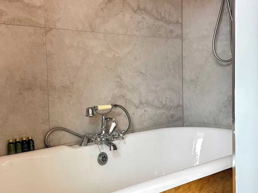 A bathroom with a freestanding bathtub, a showerhead, and a toilet.