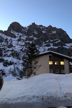 A building with a snow-covered roof and a mountain backdrop. - Gitzifurka 5 # 4-bed apartment, Dusche, WC 4-bed apartment, Dusche, WC by Interhome (Leukerbad)