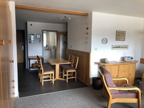 Ein kompakter Wohnraum mit Essbereich, Küchenzeile und einer kleinen Sitzecke mit Sofa und Sesseln.