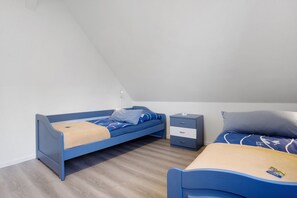 A small, modern room with two beds, a nightstand, and a wooden floor. - Apartment 'Villa Wiese  1' with Lake View, Shared Terrace and Wi-Fi (Katzow)