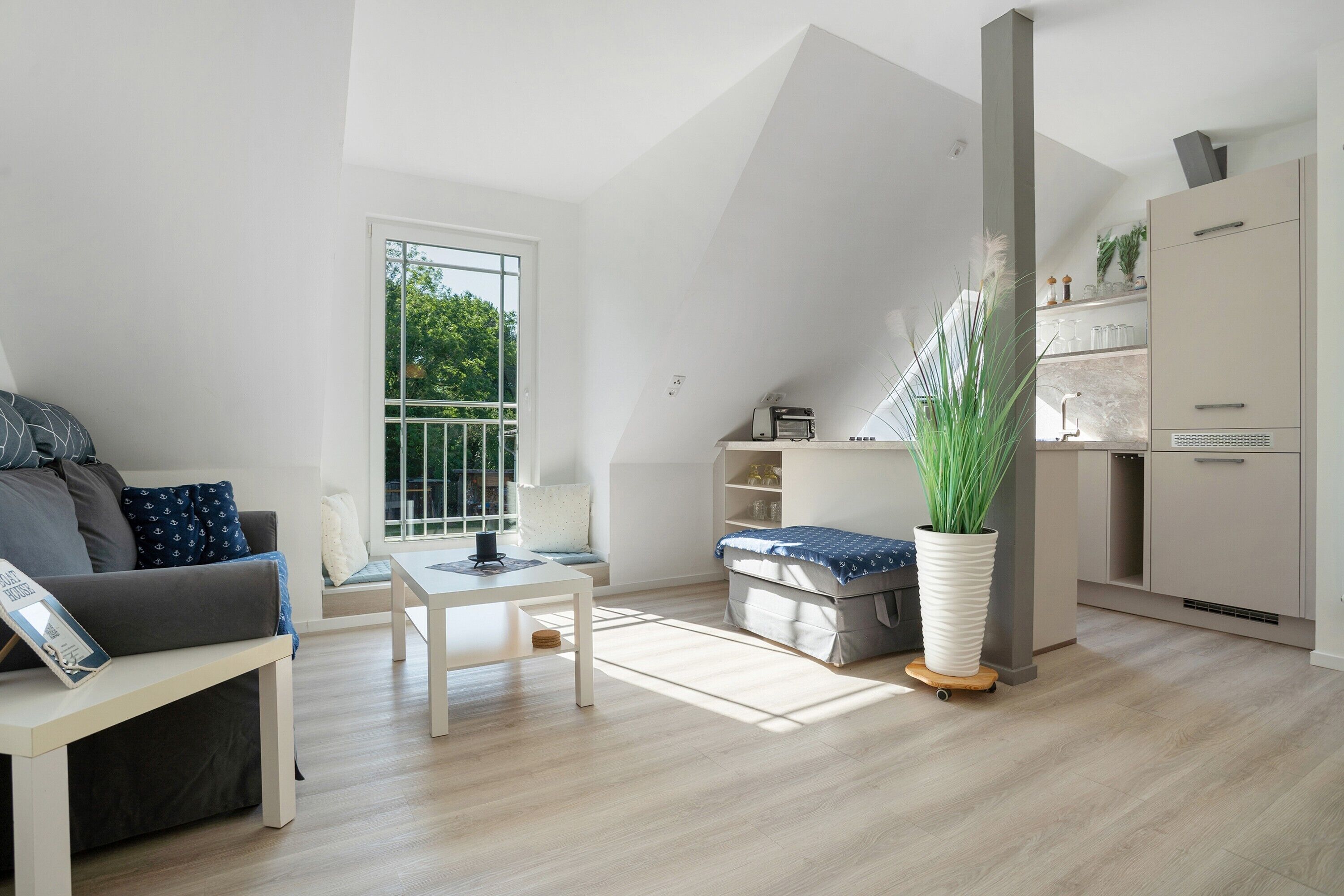 A modern living space with a loft bed, a dining table, a sofa, and a kitchen area.