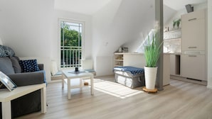 Ein stilvoller Wohnraum mit Schlafpodest, Esstisch, einer Couch und einer Küchenzeile.