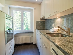 A modern kitchen with a window, granite countertops, and stainless steel appliances. - Utoring 412 by Arosa Holiday Appartement/Fewo, Dusche oder Bad, WC, 4-Bettwohnun by Interhome (Arosa)