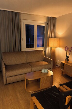 A living room with a sofa, a coffee table, a lamp, and a chair. - Majesta Leukerbad # 3-bed apartment, Bad, WC by Interhome (Leukerbad)