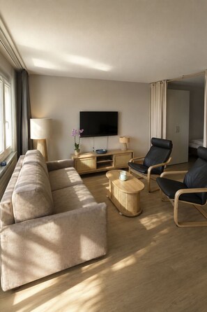 A modern living room with a sofa, two armchairs, a coffee table, a TV, and a wardrobe. - Majesta Leukerbad # 3-bed apartment, Bad, WC by Interhome (Leukerbad)