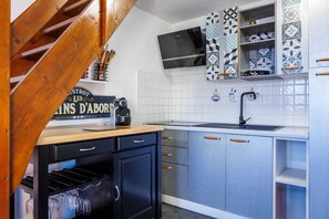 Eine Küche mit einer Holztreppe, einem schwarzen Kühlschrank und einer gefliesten Spritzschutzwand.