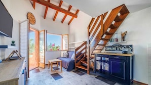 A modern kitchen with a wooden staircase, a dining area with a sofa, and a view of the outdoors. - Duplex 400 meters from the ocean with a pool in a gated community (Zonza)