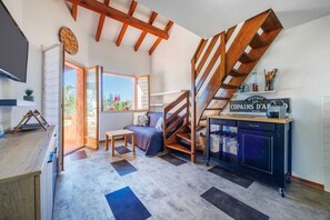 Eine moderne Küche mit einer Holztreppe, einem Essbereich mit einer Couch und Blick ins Freie.