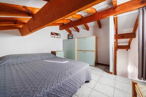 A bedroom with a bed, wardrobe, and a window with curtains. - Vrbo Property (Zonza)