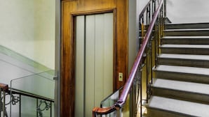 Un escalier en bois, avec une porte en bois et des rampes en métal, menant à un ascenseur.