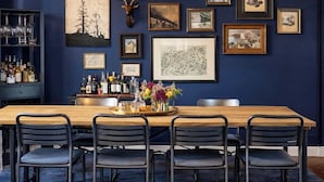 Un espace repas comprenant une longue table, six chaises et divers tableaux encadrés accrochés au mur.