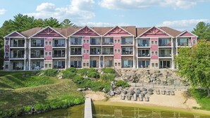 Un hotel de varios pisos con balcones, un jardín ajardinado con fuente de agua y un muro de contención de piedra.