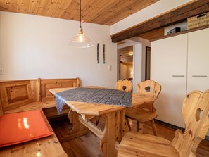 Ein Holzespeisetisch mit einem gemusterten Tischläufer, umgeben von Holzkästen mit Ausschnitten in der Rückenlehne.