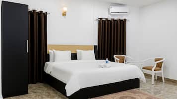 Ein Hotelzimmer mit Bett, einem Sessel, einem kleinen Tisch, einer Klimaanlage und einer Wandleuchte.