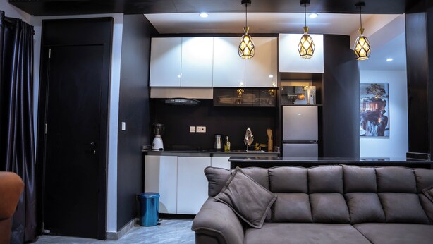 Una cocina moderna con gabinetes blancos, encimera negra y tres lámparas colgantes.
