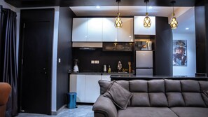 A modern kitchen with white cabinets, a black countertop, and three pendant lights. - Filial Court Stays (Abuja)