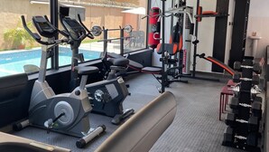 Un gimnasio con equipo cardiovascular, máquinas de pesas y un saco de boxeo.