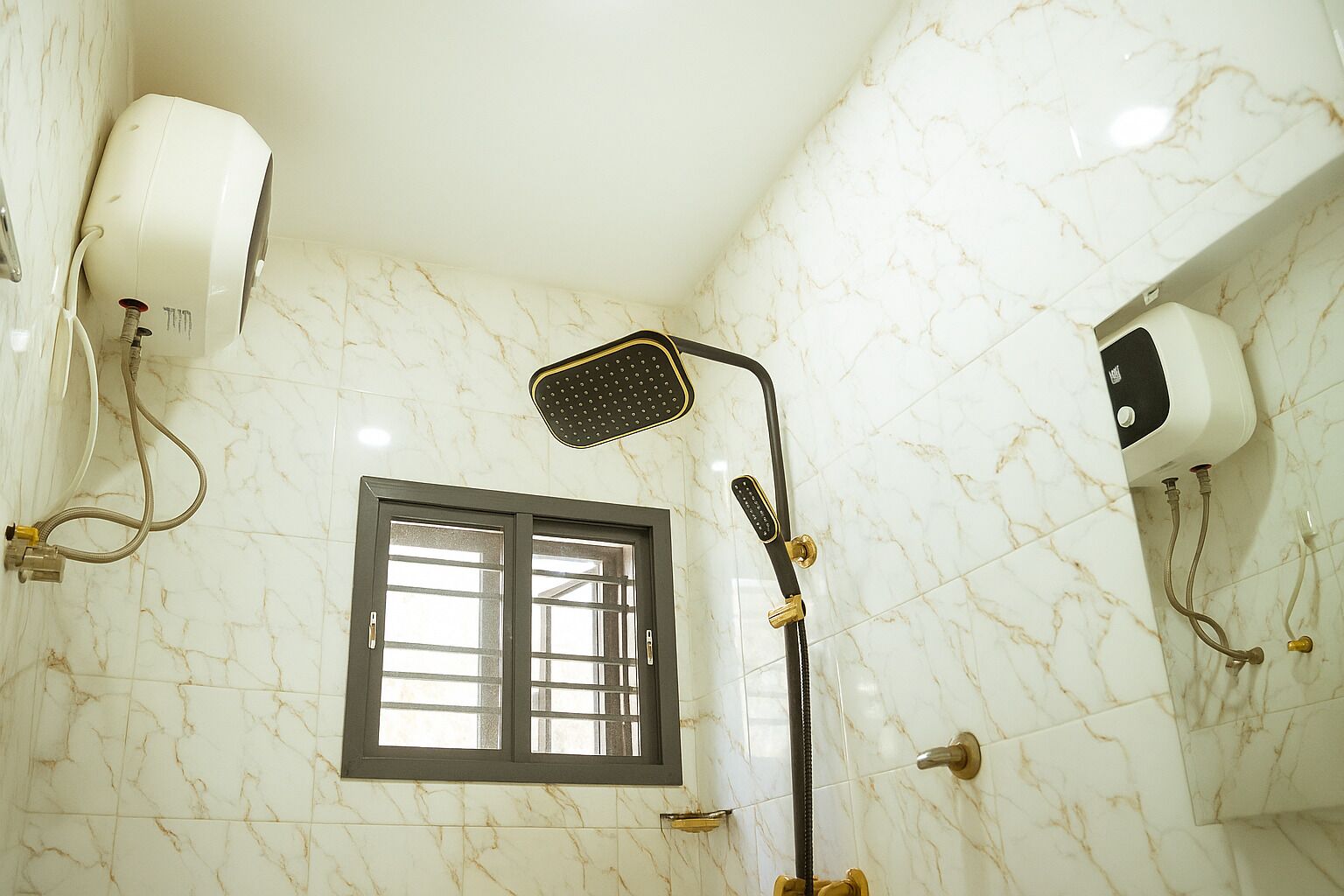 Un bagno con doccia, finestra e pareti in marmo.