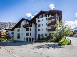 A modern multi-story building with balconies, a parking area, and a mountain backdrop. - Brüggli A-24 by Arosa Holiday Appartement/Fewo, Bad, WC, 3-Bettwohnung by Interhome (Arosa)