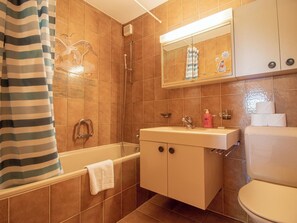 A bathroom with a bathtub, a sink, and a toilet. - Brüggli A-24 by Arosa Holiday Appartement/Fewo, Bad, WC, 3-Bettwohnung by Interhome (Arosa)