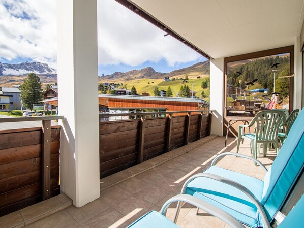 A balcony with a view of mountains, a wooden fence, and blue chairs. - Brüggli A-24 by Arosa Holiday Appartement/Fewo, Bad, WC, 3-Bettwohnung by Interhome (Arosa)