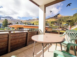 A balcony with a round table and chairs, overlooking a mountainous landscape with buildings and a clear sky. - Brüggli A-24 by Arosa Holiday Appartement/Fewo, Bad, WC, 3-Bettwohnung by Interhome (Arosa)