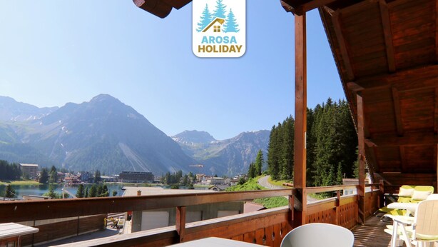 Eine Holzterrasse mit Tischen und Stühlen mit Blick auf eine gebirgige Landschaft.