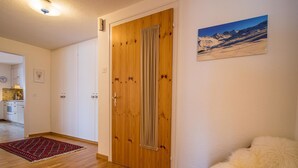 Ein Zimmer mit Holztür, einem roten Teppich mit Muster und einem weißen, flauschigen Gegenstand.