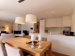 A modern kitchen with white cabinets, a dining table with candles, and a living area with a sofa and lamp. - Salis 02 by Arosa Holiday Appartement/Fewo, Dusche und Bad, WC, 4-Bettwohnung by Interhome (Arosa)