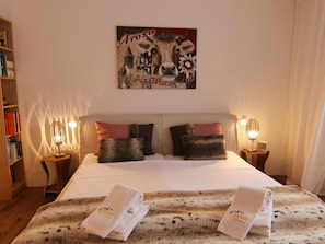 A hotel room with a large bed, two pillows, a painting above the bed, a bookshelf, and two nightstands with lamps. - Salis 02 by Arosa Holiday Appartement/Fewo, Dusche und Bad, WC, 4-Bettwohnung by Interhome (Arosa)