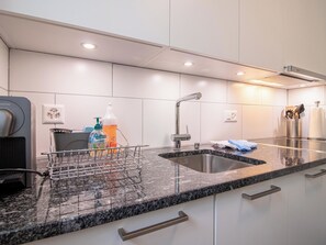 A modern kitchen with a granite countertop, stainless steel sink, and a coffee machine. - Casa Viktoria A37 by Arosa Holiday Appartement/Fewo, Dusche, WC, 4-Bettwohnung by Interhome (Arosa)
