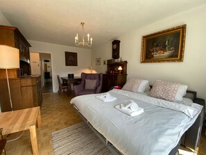 A hotel room with a bed, a desk, a chair, a dining table, a chandelier, and a painting on the wall. - Casa Viktoria A37 by Arosa Holiday Appartement/Fewo, Dusche, WC, 4-Bettwohnung by Interhome (Arosa)