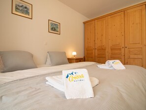 A hotel room with a bed, two pillows, a nightstand with a lamp, wooden wardrobe, and two framed pictures on the wall. - Casa Viktoria A37 by Arosa Holiday Appartement/Fewo, Dusche, WC, 4-Bettwohnung by Interhome (Arosa)