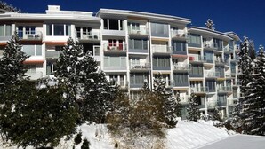 Een hotel met meerdere verdiepingen en balkons, omringd door met sneeuw bedekte bomen.