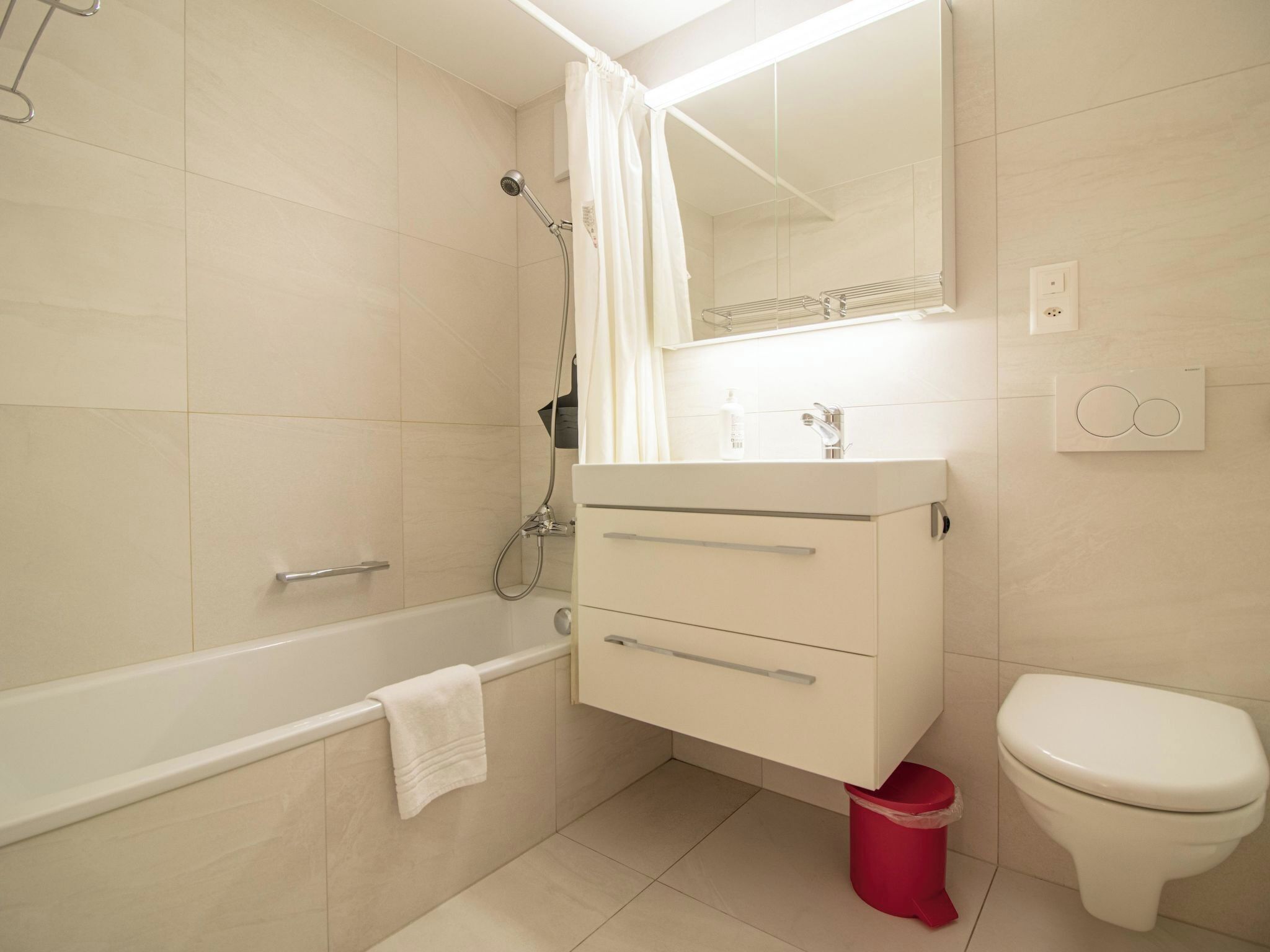 Een moderne badkamer met een badkuip, toilet en een wastafel met een spiegel erboven.