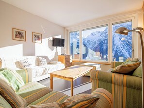 Ein gemütliches Wohnzimmer mit einer Couch, einem Holztisch und einem Fernseher.