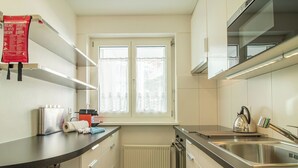 Een moderne keuken met een raam, roestvrijstalen apparatuur en een rode tas op het aanrecht.