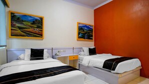 A hotel room with two beds, a desk, and two paintings on the wall. - Lima Residence Deluxe Twin (Bandar Lampung)