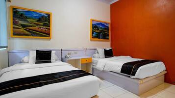A hotel room with two beds, a desk, and two paintings on the wall.