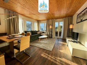 Un intérieur moderne avec un plafond en bois, un canapé, une table à manger et un téléviseur.