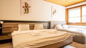 A bedroom with a wooden ceiling, two beds, and artwork on the walls. - Miraflor Betty by Arosa Holiday Appartement/Fewo, Dusche und Bad, WC, 8-Bettwohn by Interhome (Arosa)