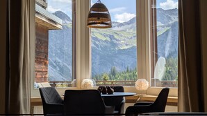 A room with a table and chairs, large windows with mountain views, and a hanging light fixture. - Miraflor Betty by Arosa Holiday Appartement/Fewo, Dusche und Bad, WC, 8-Bettwohn by Interhome (Arosa)